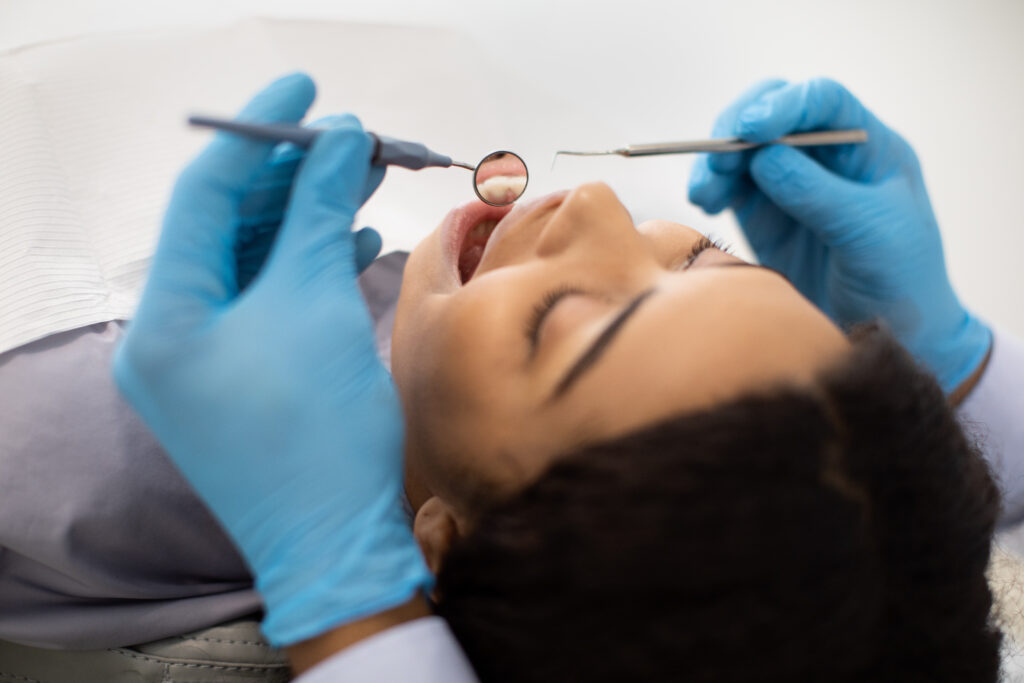Dentist in blue gloves examining patient's teeth during dental procedure at Smile Loft.